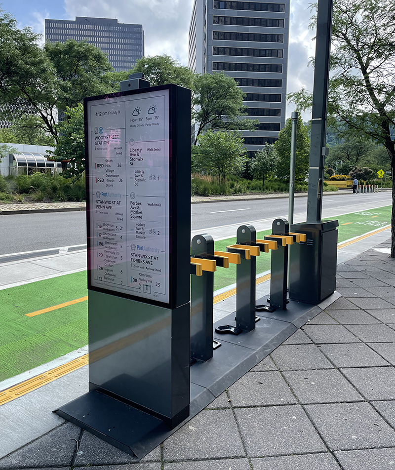 A Move PGH mobility hub, with an e-scooter docking station from Swiftmile and Port Authority bus timings on a display provided by TransitScreen.